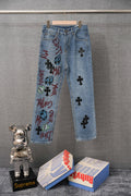 Light blue denim pants with colorful graffiti print and black cross patches on legs
