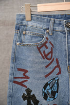 Light blue denim pants close-up of front pocket with red graffiti lettering and blue face