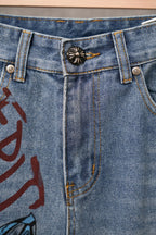 Light blue denim jeans front with button fly and black sun-shaped patch on waistband.