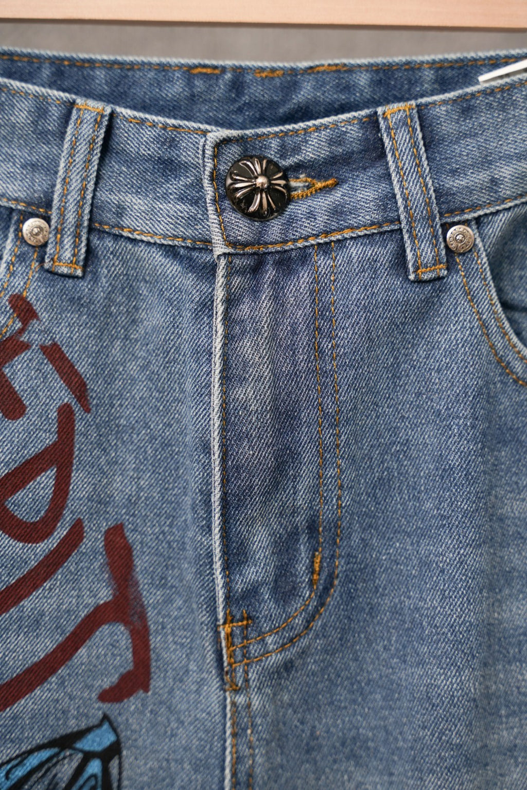 Light blue denim waistband with button fly and small flower emblem patch