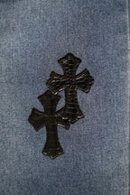 Light blue denim fabric with three stitched black cross patches.