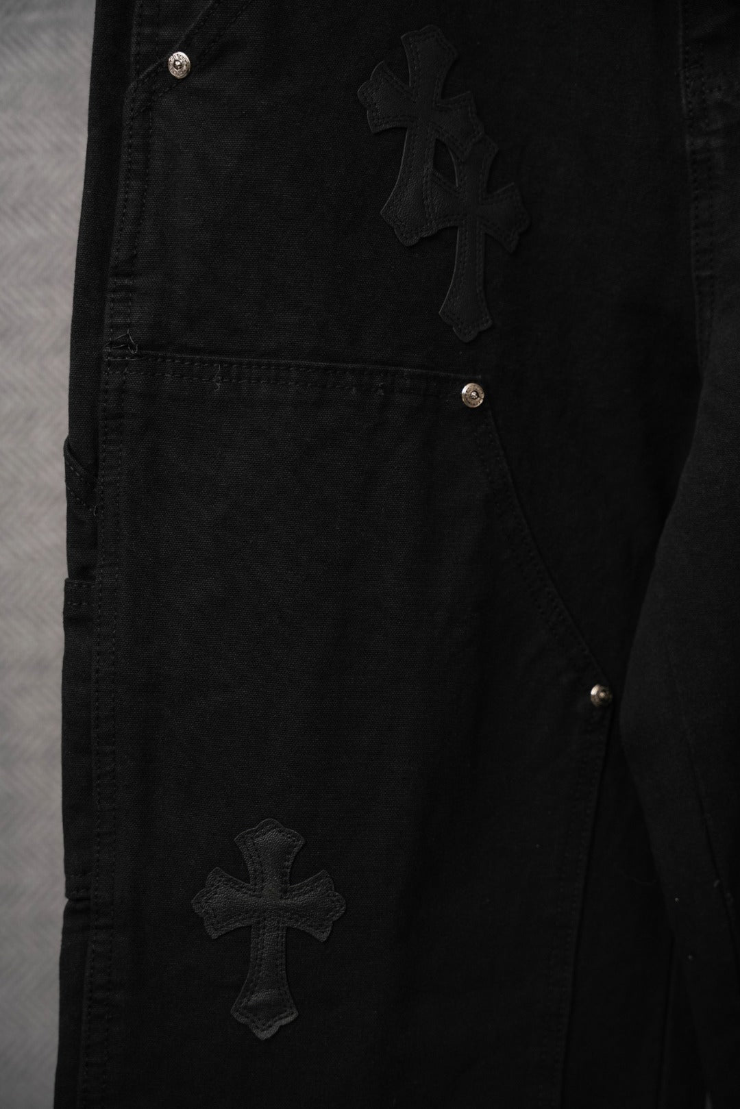 Black pants with cross applique and silver metal rivet pocket details