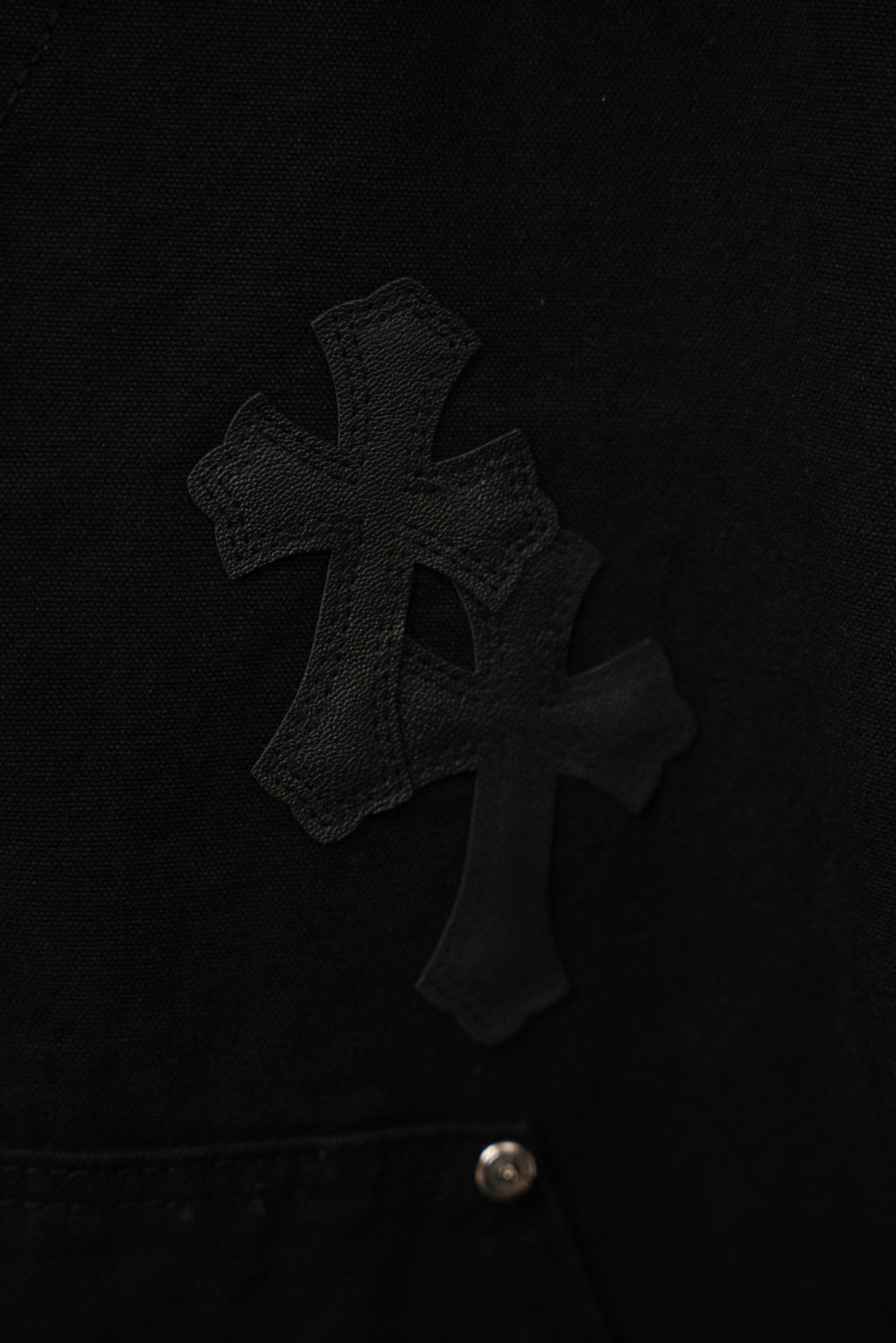Black cross-embroidered cargo pants with metal button closure