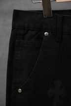 Black chrome pants close-up with diagonal pocket seam and cross embroidery