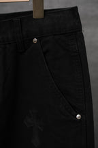Black chrome pants close-up with button waistband and cross embroidery on leg