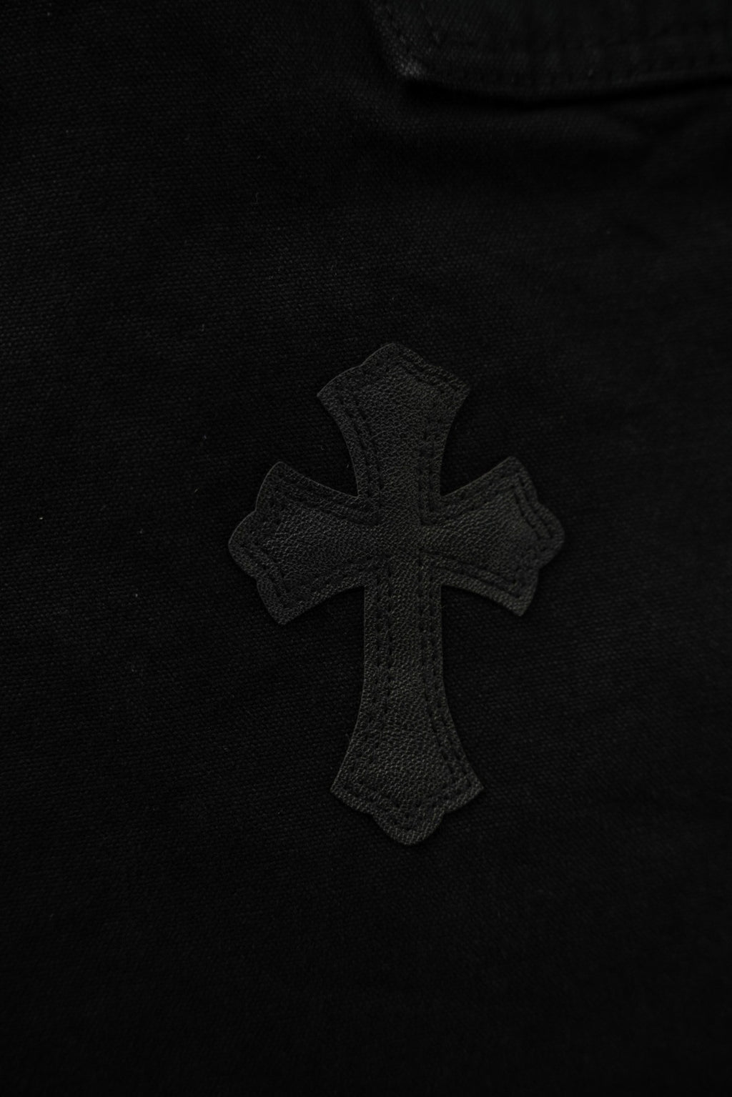 Black pants with small embroidered cross applique on leg