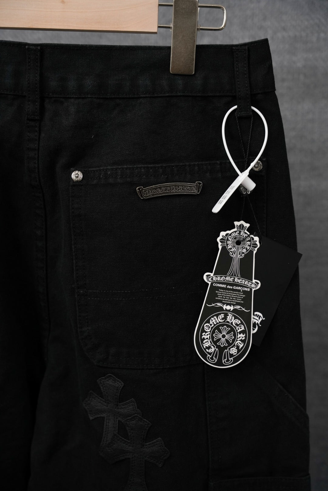 Black pants with front pocket, snap hardware, and cross appliqué tag