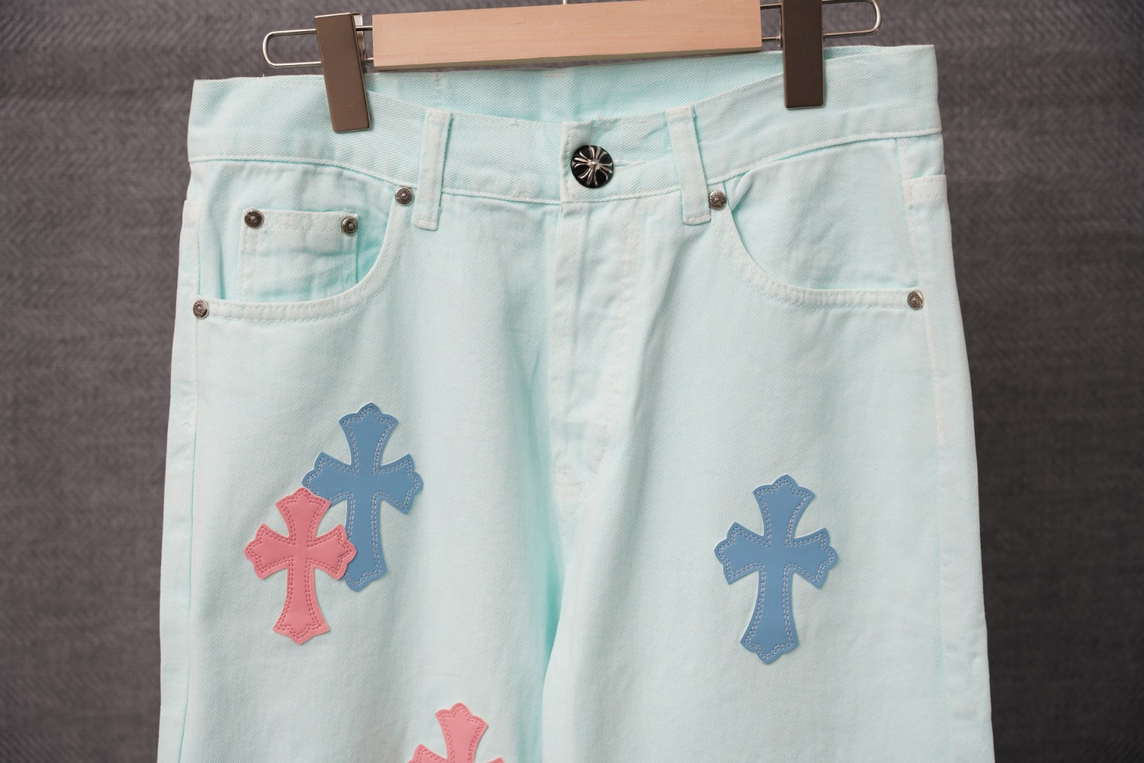 Light blue denim pants with front pockets and visible cross patches at the hip.