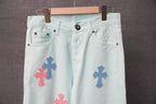 Light blue denim pants with multiple colorful cross patches and a black waistband button.
