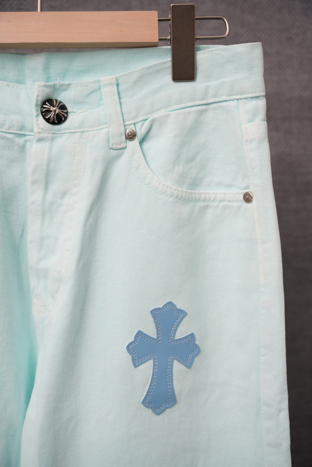 Light blue denim pants with a large blue cross patch near the front thigh.