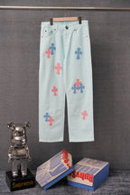 Light blue denim pants with colorful cross patches and front button closure