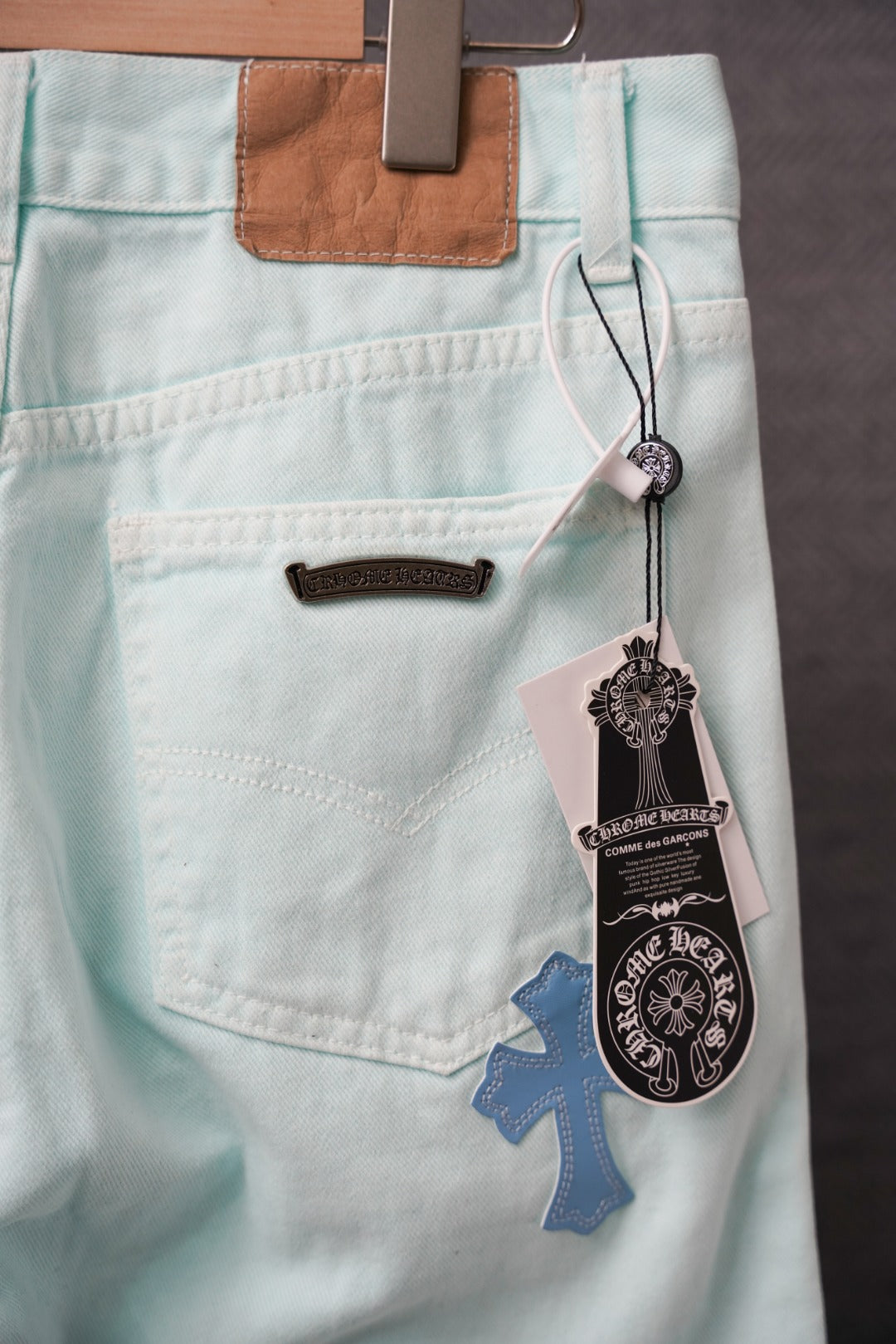 Light blue pants with front pocket, black patch trim, and hanging product tags