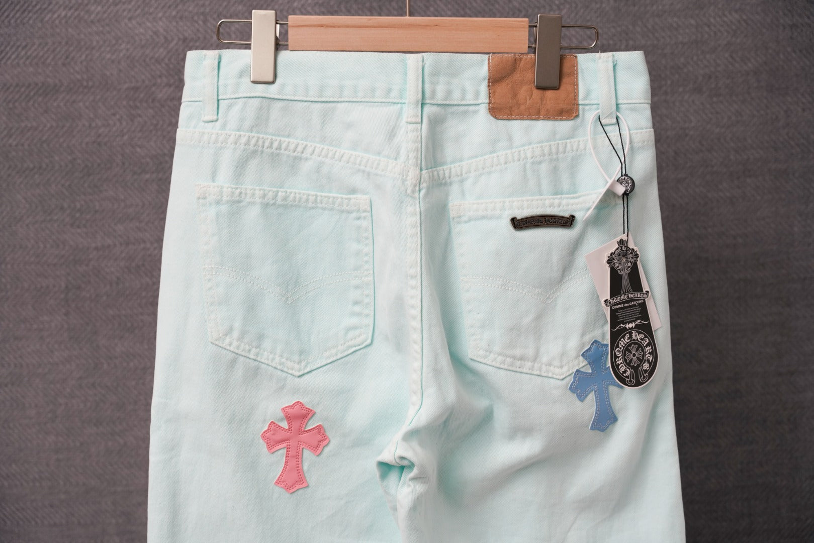 Light blue pants with stitched cross patches on front, button fly and belt loops