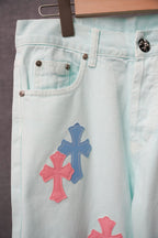 Light blue denim pants with front pockets and large pink and blue cross patches.