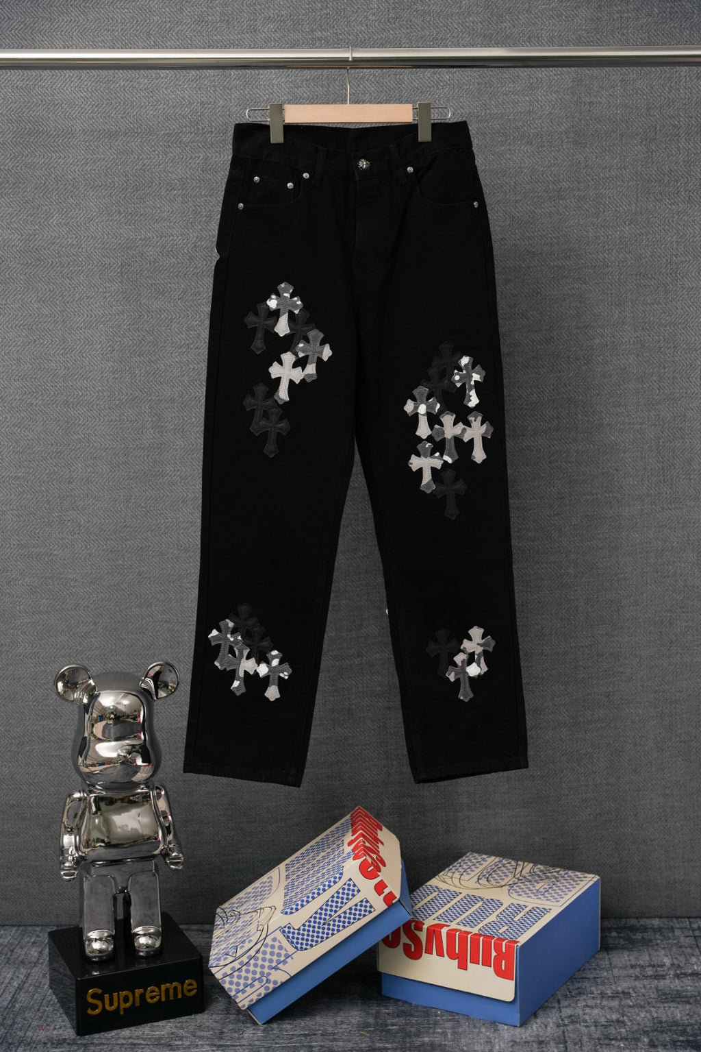 Black jean-style pants with silver cross appliqué, straight leg and button waist