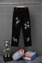 Black jean-style pants with silver cross appliqué, straight leg and button waist