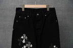 Black denim-style pants with white cross patches on the leg