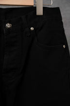 Black pants side pocket with metallic button and white cross appliqué