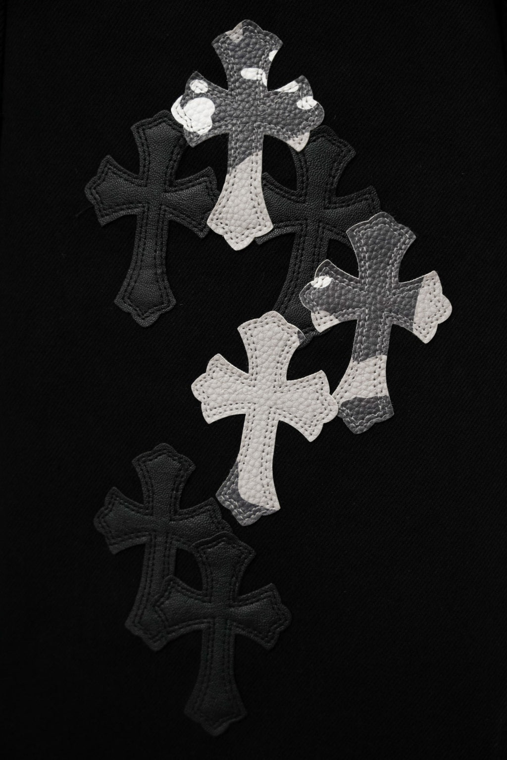 Black pants featuring large silver cross appliqué graphic on the front
