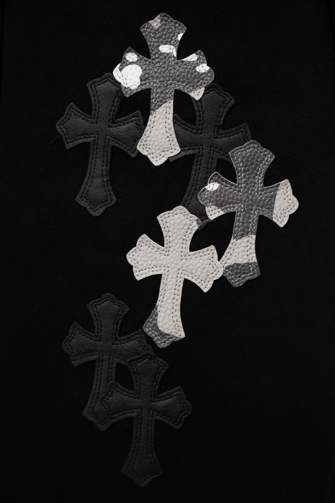 Black pants featuring large silver cross appliqué graphic on the front