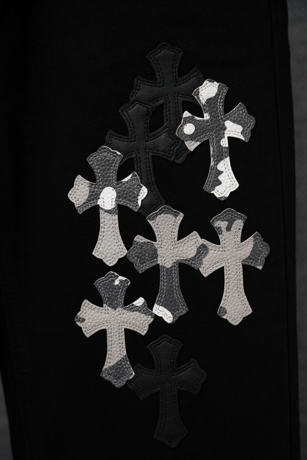 Black pants with cluster of silver cross appliqué across the leg