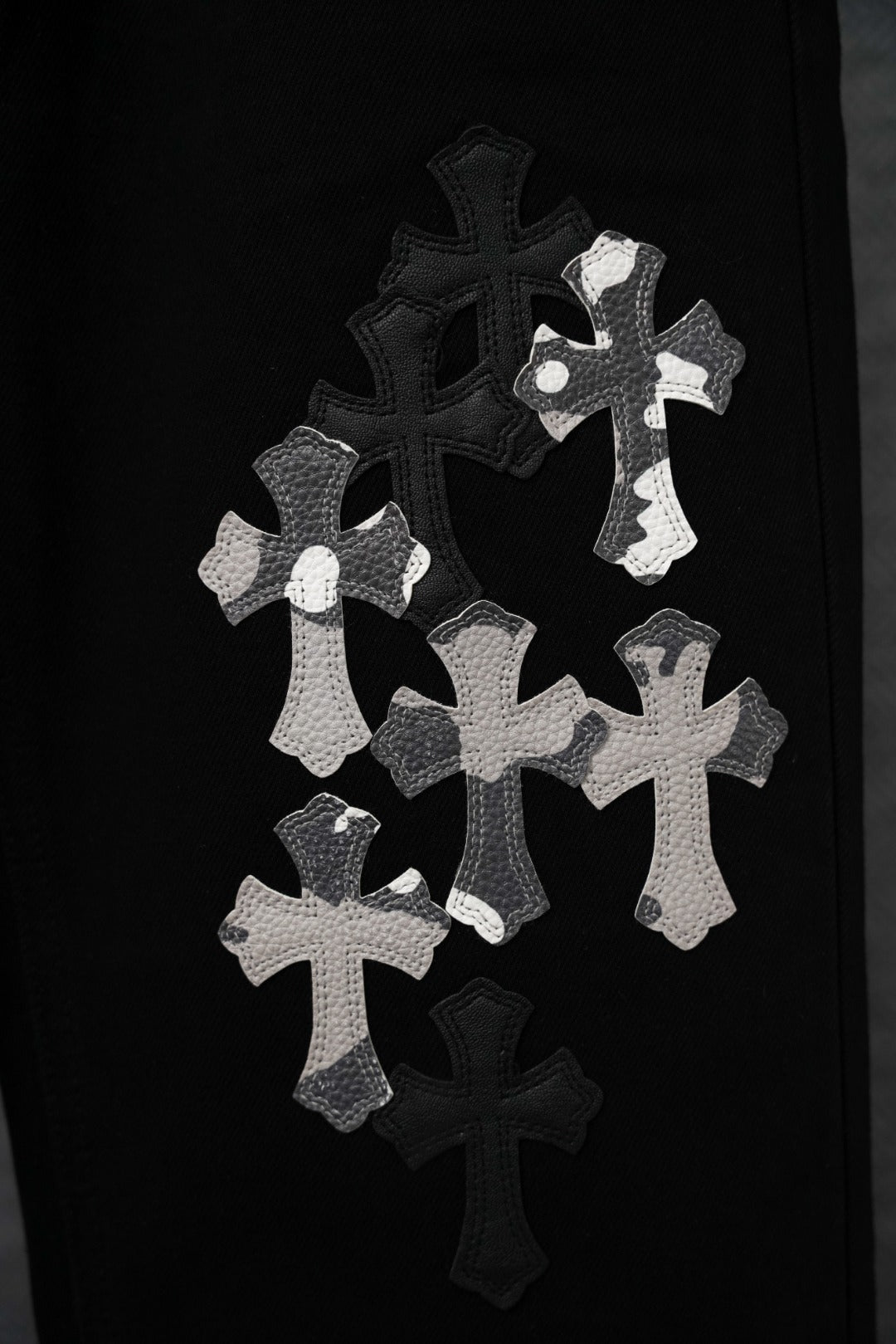 Black pants leg with multiple white cross appliqué designs