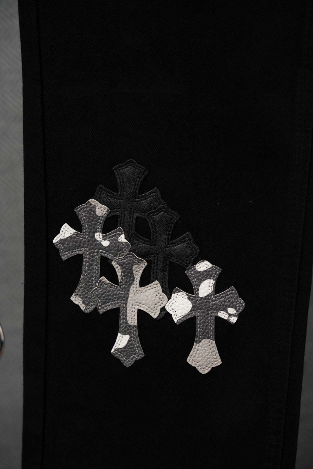 Black pants with silver cross appliqué motif on the lower leg
