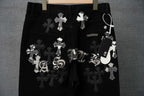 Black pants with multiple cross patches, stitched letters, and belt tag
