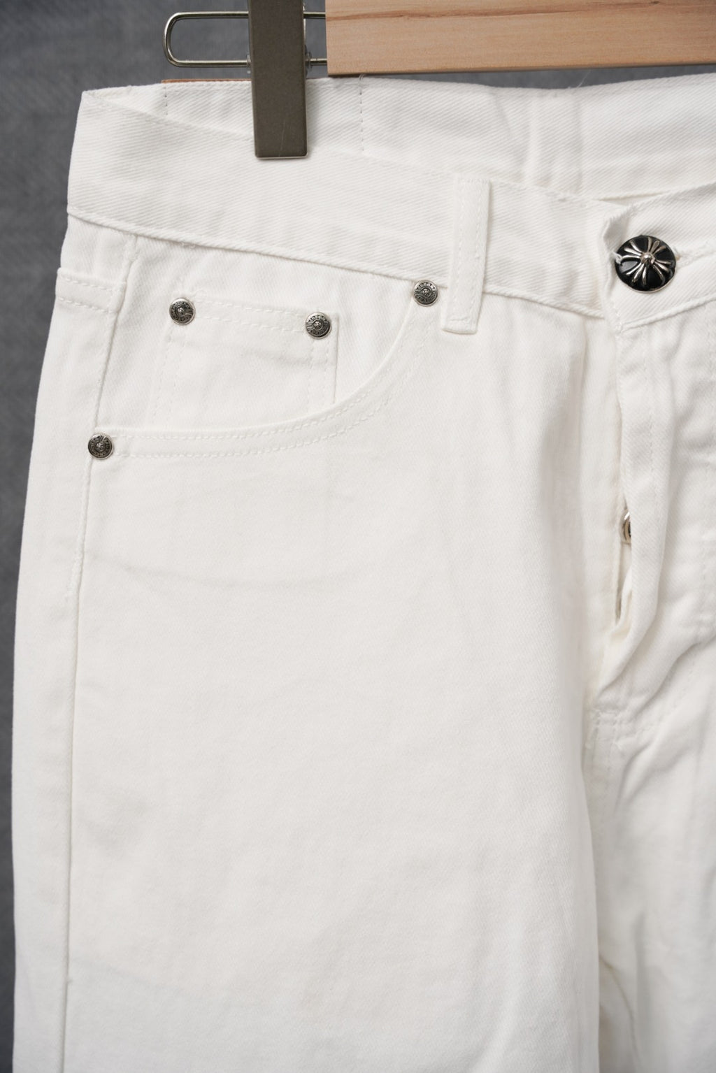White pants with front pockets, belt loops, and small metal buttons