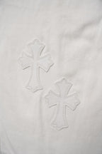 Close-up of stitched cross motifs on white pants fabric