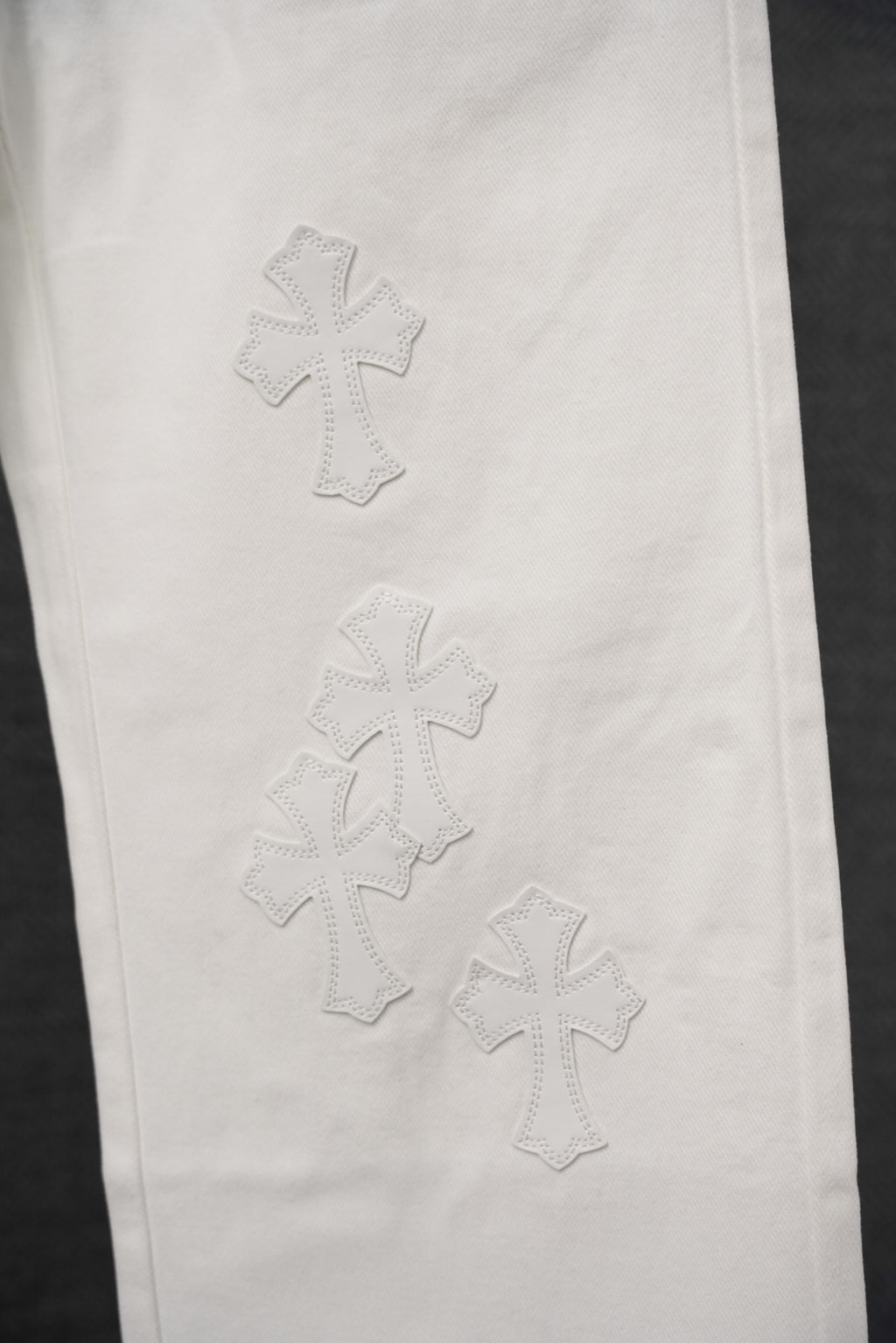 White pants with stitched cross patterns on the leg