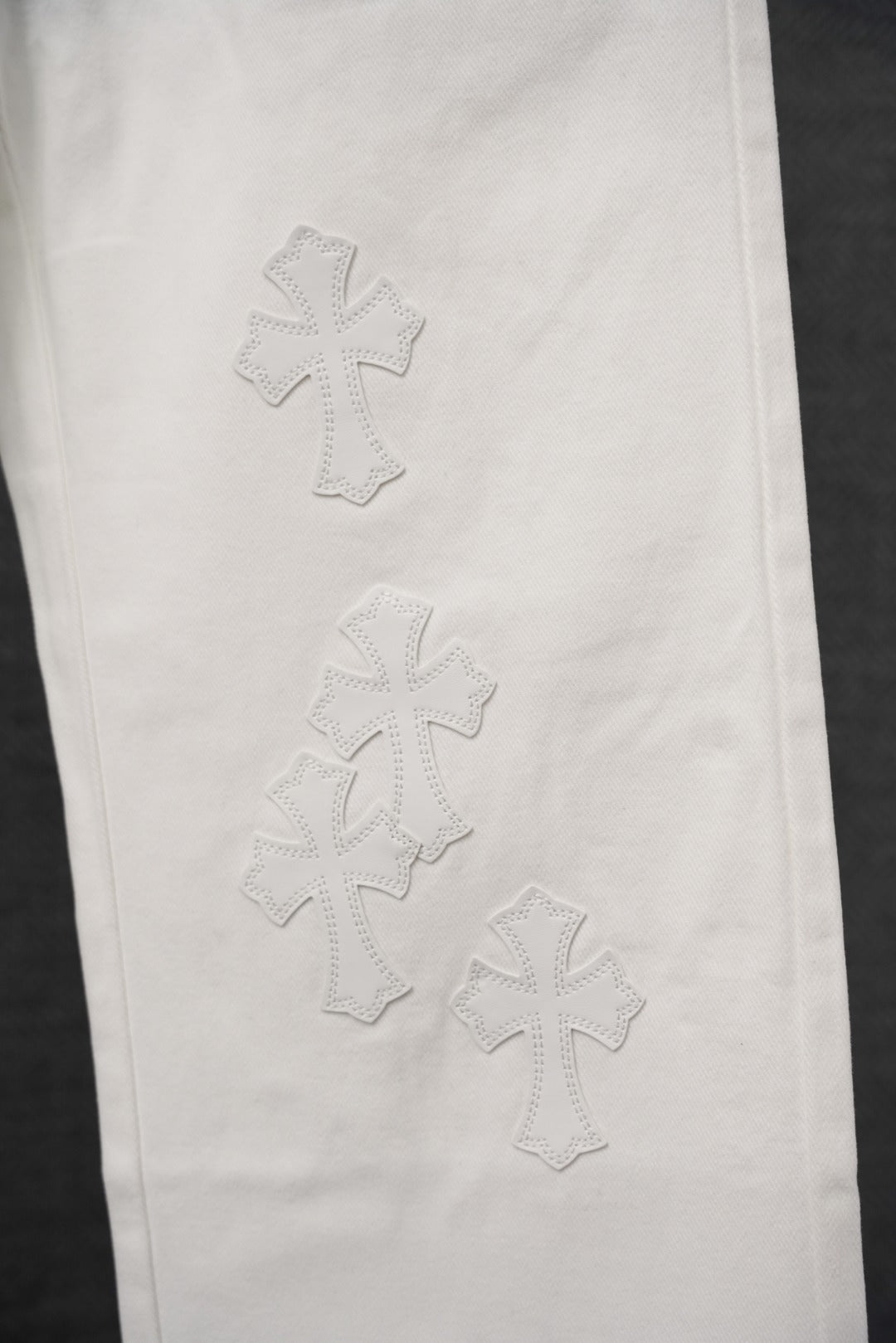 White pants with stitched cross patterns on the leg