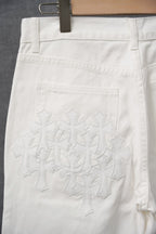 White pants with decorative cross embroidery on front pocket