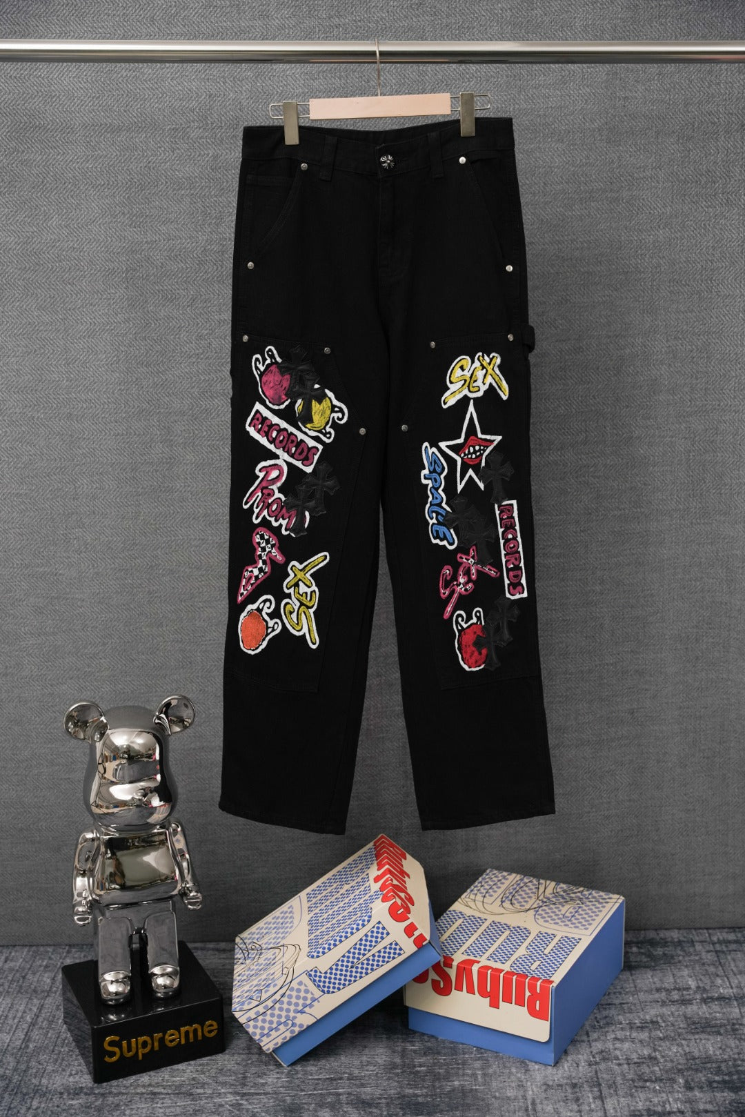 Black cargo pants with colorful embroidered graphic patches on legs, front view
