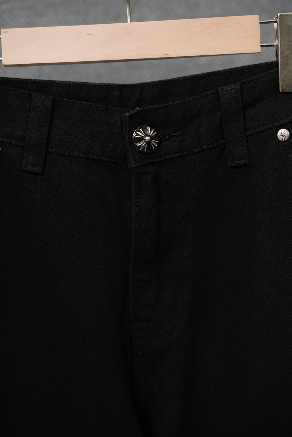 Black cargo pants close-up of waist area with decorative emblem and belt loops