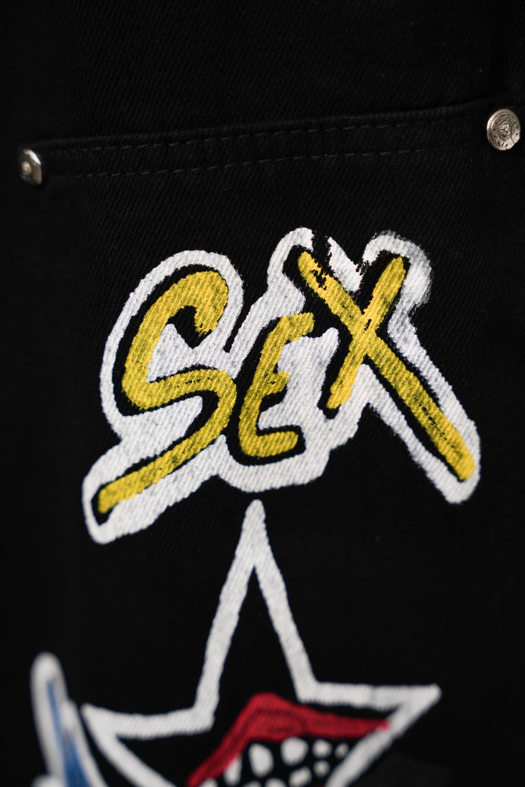 Black cargo pants close-up of embroidered logo-style text and small star patch