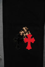 Black pants side panel with red cross and leopard patch motif.