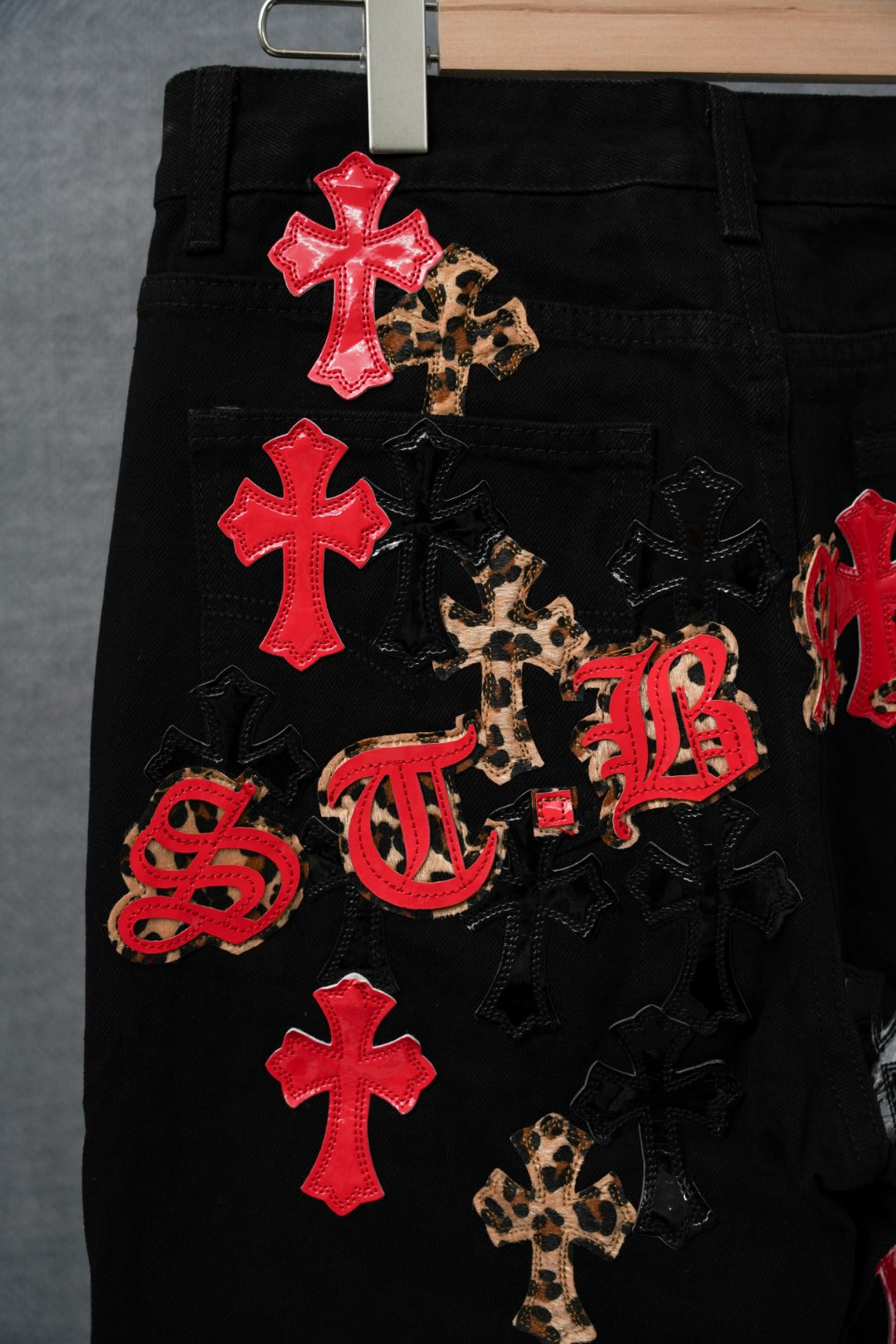 Black pants with red cross patches, leopard motifs, and red letter appliques