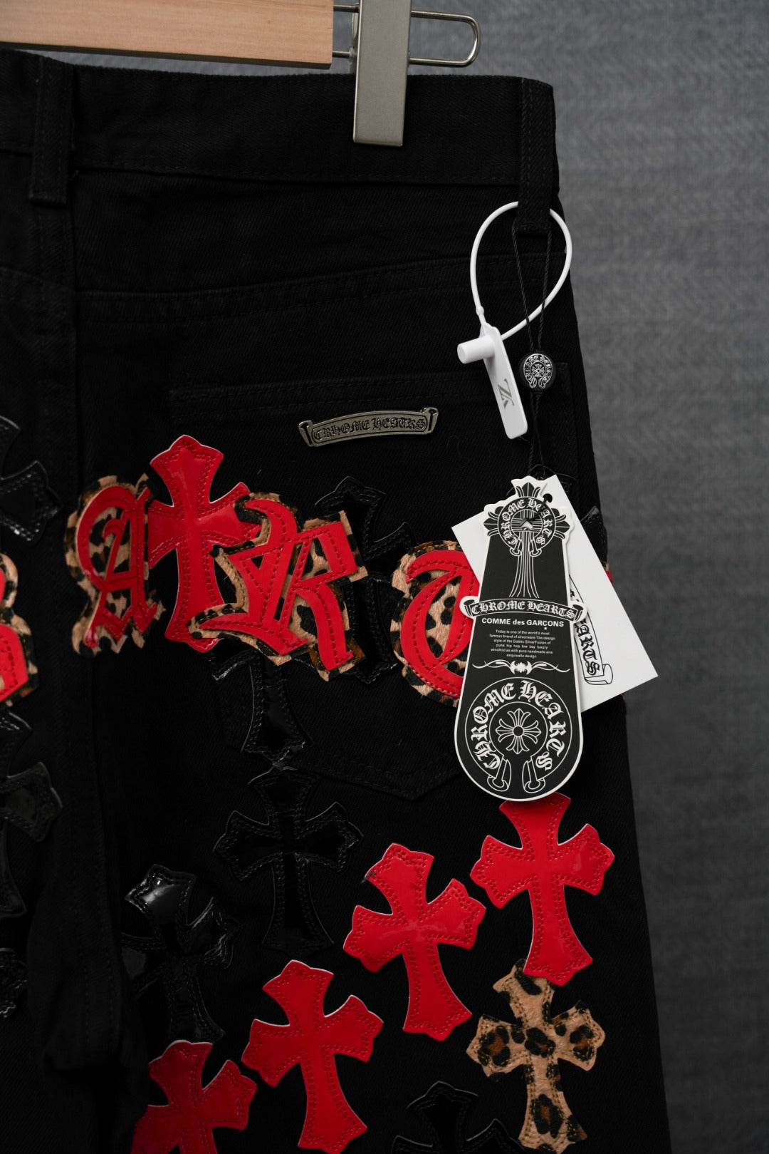 Black pants with red cross patches, leopard trim, and decorative patches
