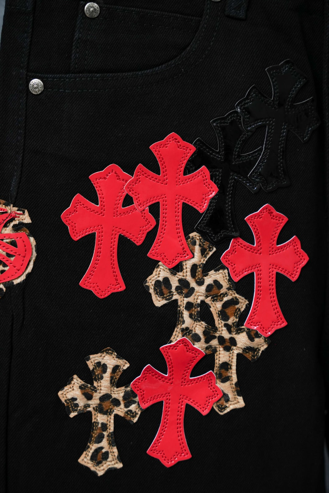 Black pants pocket with red cross appliques and leopard pattern cluster.