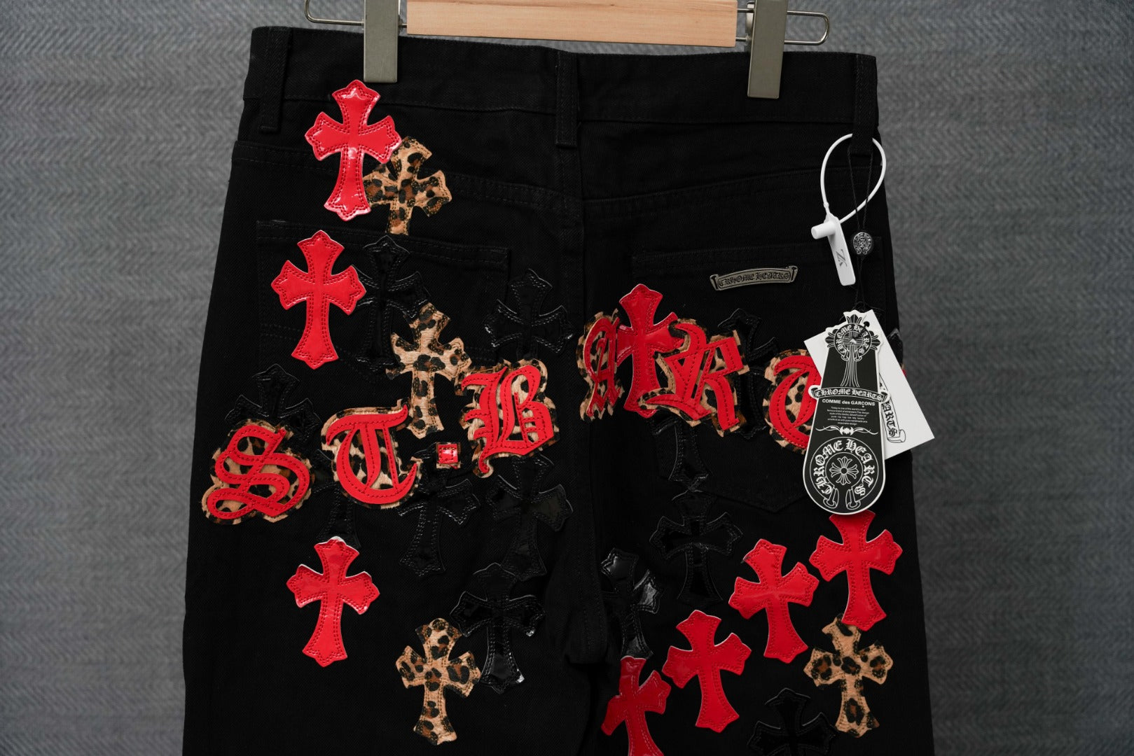 Black pants with red cross patches, leopard motifs, and ornate lettering
