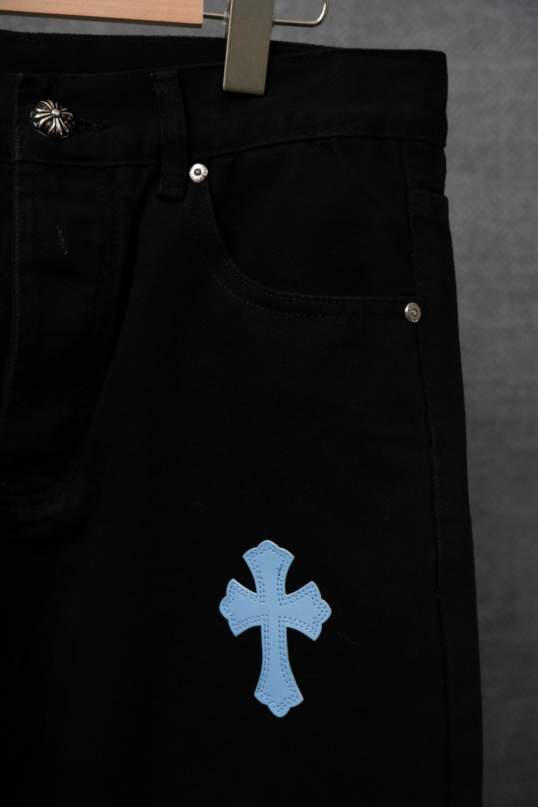 Chrome pants close-up: black pocket with blue cross patch on front leg