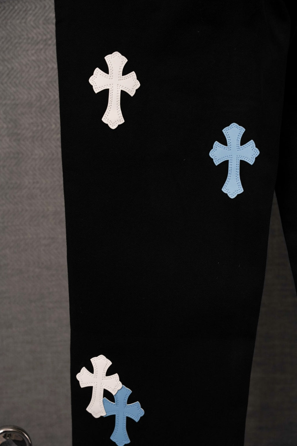 Black pants with white and light blue cross appliques on front leg