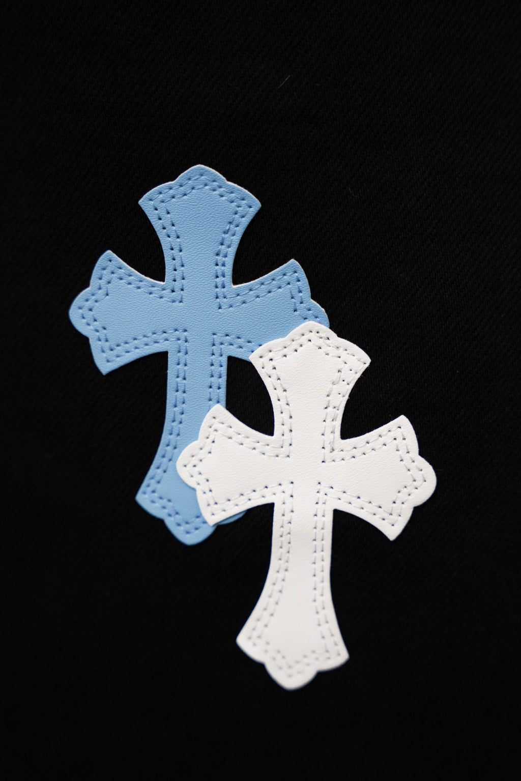 Chrome pants, close-up of light blue and white cross patches on fabric