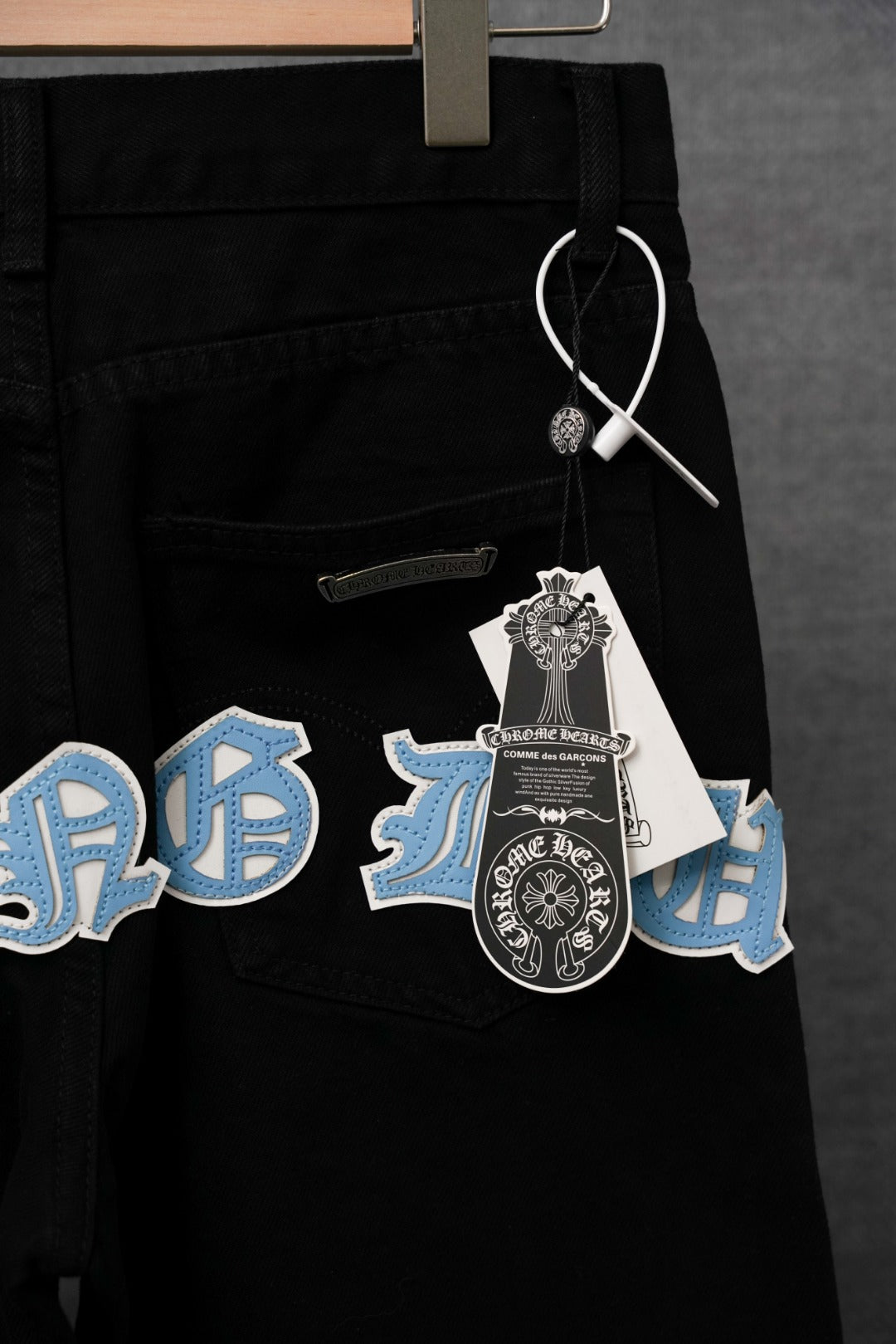 Black pants with light blue and white cross appliques on front pockets