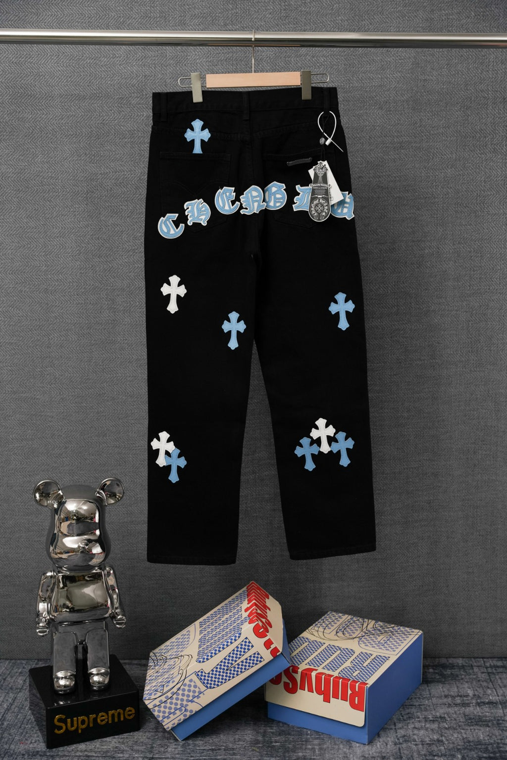 Chrome pants on hanger, black with multiple blue cross patches and front pockets