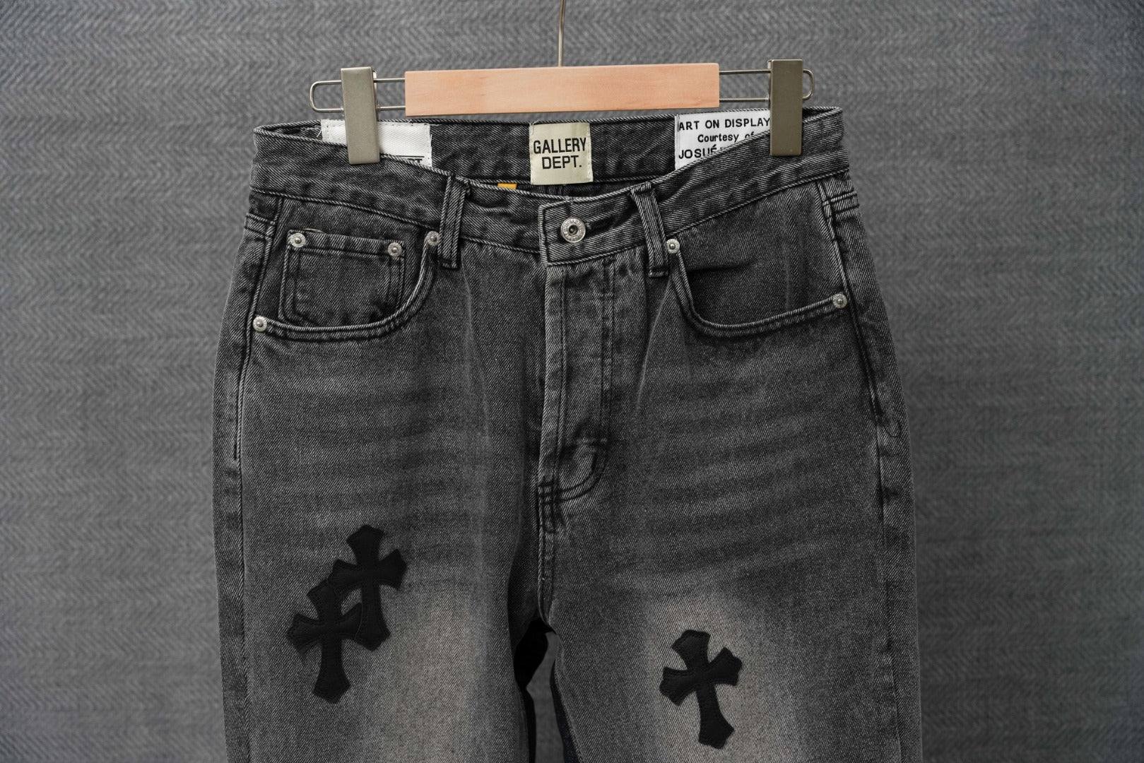 Dark denim pants with button fly and cross patches on the legs