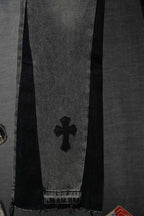 Black denim pants detail with four-petal cross graphic near hem.