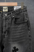 Dark denim pants with front button waist, pocket stitching, and cross emblem