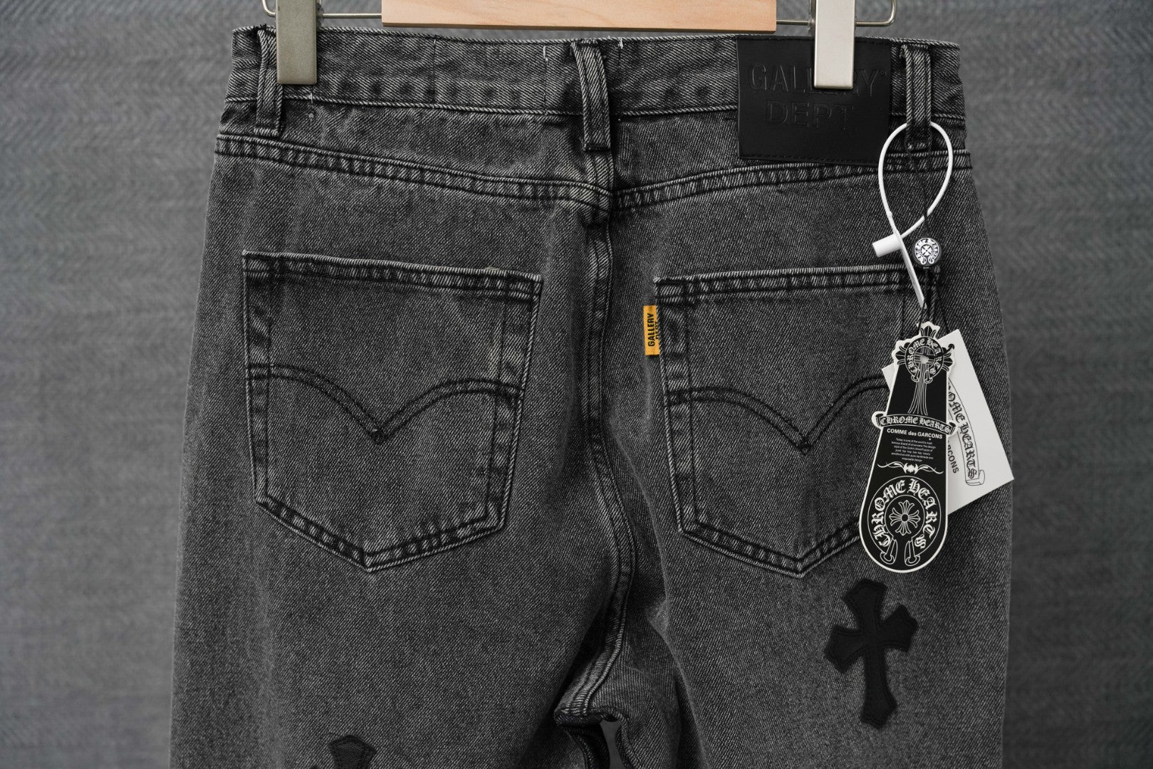 Black denim pants with heart-shaped front pockets and four-petal cross graphic detail.